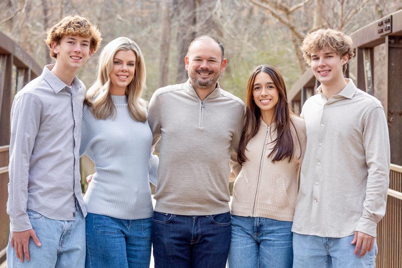 The Dixon family stands on a bridge smiling for a family photo in Atlanta, GA